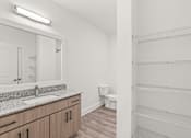 Thumbnail 17 of 30 - A white bathroom with a sink, mirror, and toilet.