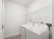 Thumbnail 19 of 30 - A white washing machine and dryer in a small laundry room.