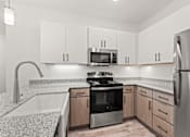 Thumbnail 14 of 30 - A modern kitchen with a stainless steel refrigerator, microwave, and oven.