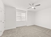 Thumbnail 15 of 30 - A room with a ceiling fan and carpeted floor.