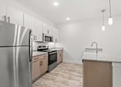 Thumbnail 10 of 30 - A kitchen with a stainless steel refrigerator, microwave, oven, and sink.