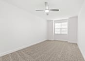 Thumbnail 11 of 30 - A room with a ceiling fan and carpeted floor.