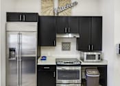 Thumbnail 4 of 8 - a kitchen with black cabinets and stainless steel appliances and a refrigerator