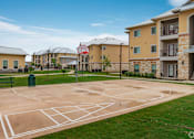 Thumbnail 14 of 16 - A basketball court in front of apartment buildings.