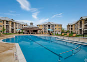 Thumbnail 16 of 16 - A large swimming pool in front of apartment buildings.