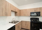 Thumbnail 1 of 9 - A kitchen with wooden cabinets and black appliances.