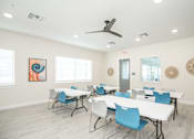 Thumbnail 6 of 9 - A room with a white table and blue chairs.