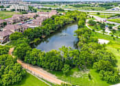 Thumbnail 1 of 12 - A river flows through a green area with apartment buildings on the side.
