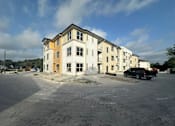 Thumbnail 3 of 3 - an apartment building with a car parked in a parking lot