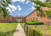 Thumbnail 5 of 39 - A long brick building with a walkway in front.