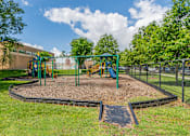Thumbnail 21 of 39 - A playground with a green swing set and a slide.