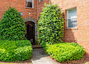 Thumbnail 13 of 39 - A red brick building with green bushes in front.