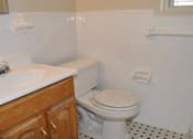 Thumbnail 37 of 39 - A white toilet in a bathroom with a sink and wooden cabinets.