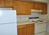 Thumbnail 28 of 39 - A kitchen with white refrigerator, stove, and wooden cabinets.