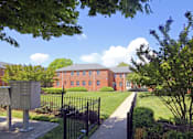 Thumbnail 8 of 39 - A red brick building with a black fence in front of it.