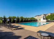 Thumbnail 48 of 137 - a pool with chairs and a table in front of a building