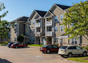 Thumbnail 101 of 137 - an apartment building with cars parked in a parking lot