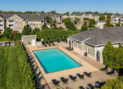 Thumbnail 114 of 137 - an aerial view of a swimming pool with chairs around it and apartments in the background