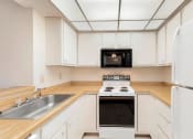 Thumbnail 24 of 31 - a kitchen with white cabinets and a stove and a sink