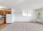 Thumbnail 31 of 38 - an empty living room with a kitchen with a white refrigerator