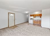 Thumbnail 34 of 38 - an empty living room with a kitchen with a white door