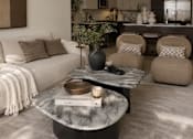 Thumbnail 8 of 16 - A modern living room with a white sofa, a coffee table, and a large vase.