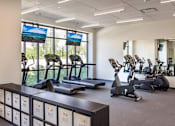 Thumbnail 13 of 25 - A gym with treadmills, exercise bikes, and a row of storage boxes at The Olivia Apartments, Indiana