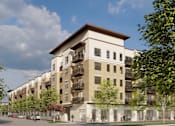 Thumbnail 2 of 16 - A modern apartment building with a mix of beige and white exterior walls, surrounded by trees and a clear blue sky.