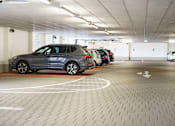 Thumbnail 10 of 16 - A parking garage with a grey car in the foreground.