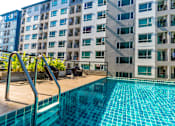 Thumbnail 14 of 16 - A swimming pool in front of a multi-story residential building.