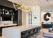 Thumbnail 20 of 25 - A modern kitchen with a white countertop and black cabinets at The Olivia Apartments, Indiana