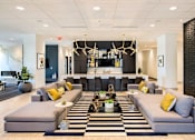 Thumbnail 18 of 25 - A modern living room with a black and white striped rug and grey couches at The Olivia Apartments, Carmel, IN, 46032