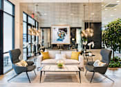 Thumbnail 19 of 25 - A modern living room with a large painting on the wall and a comfortable seating area at The Olivia Apartments, Indiana, 46032