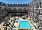 Thumbnail 2 of 35 - A large pool surrounded by a fence and a building in the background.