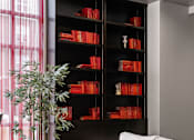 Thumbnail 29 of 35 - A living room with a white sofa and a bookshelf filled with red books.