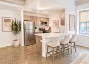 Thumbnail 5 of 20 - A kitchen with a white countertop and wooden bar stools.