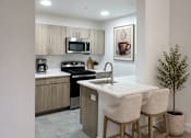 Thumbnail 7 of 20 - A kitchen with a white countertop and wooden bar stools.