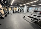 Thumbnail 5 of 14 - A spacious gym with a variety of equipment including treadmills, weights, and a bench press.