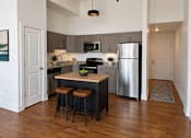 Thumbnail 6 of 15 - A kitchen with a wooden island and stools.