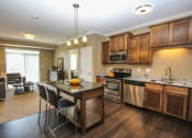 Thumbnail 8 of 33 - a kitchen with a center island and a living room in the background at The Flats at Cedar Grove, Eagan