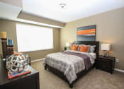 Thumbnail 10 of 33 - a bedroom with a bed and nightstand with a lamp on top of it at The Flats at Cedar Grove, Eagan, MN, 55122