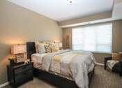 Thumbnail 4 of 33 - a bedroom with a bed and nightstand with a lamp on top of it at The Flats at Cedar Grove, Eagan, MN, 55122