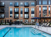 Thumbnail 40 of 43 - a pool with a brick building in the background at The Gallery Apartments, Burnsville, MN