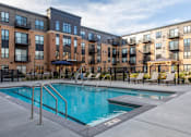 Thumbnail 3 of 43 - a swimming pool with chaise lounge chairs and a gazebo in front at The Gallery Apartments, Burnsville, MN, 55337