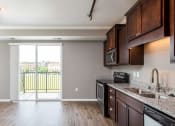 Thumbnail 17 of 44 - a kitchen with wood floors and a sliding glass door leading to a balcony  at Victoria Park and V2 Apartments, St. Paul