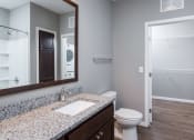 Thumbnail 19 of 44 - a bathroom with a toilet sink and mirror  at Victoria Park and V2 Apartments, Minnesota