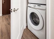 Thumbnail 9 of 42 - A white dryer is stacked on top of a white washer in a small laundry room.