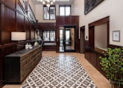 Thumbnail 11 of 42 - A hallway with a black and white tiled floor and a wooden staircase.