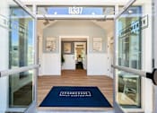 Thumbnail 3 of 35 - The entrance to a building with a blue mat that says at The Promenade at Easton Apartments, Easton, MD
