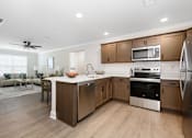 Thumbnail 11 of 35 - A modern kitchen with wooden cabinets and stainless steel appliances at The Promenade at Easton Apartments, Maryland